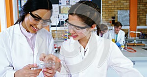Smiling schoolgirls experimenting on a piece of glass in laboratory