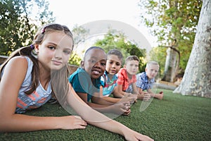 Smiling schoolkids lying on grass in campus