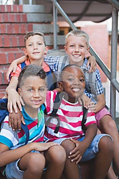 Smiling schoolkids sitting on staircase at school