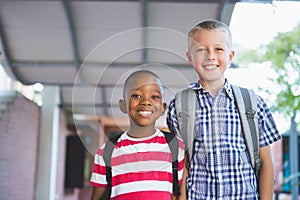 Smiling schoolkids standing in corridor