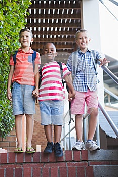 Smiling schoolkids standing on staircase at school