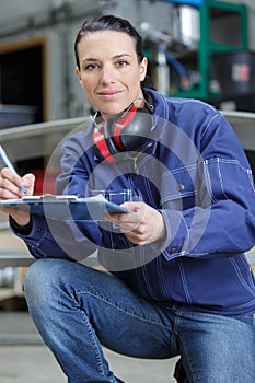 Smiling scientist holding clipboard in factory