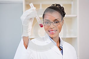 Smiling scientist showing test tube with red fluid