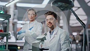 Smiling scientists looking camera in modern laboratory close up. Two researchers