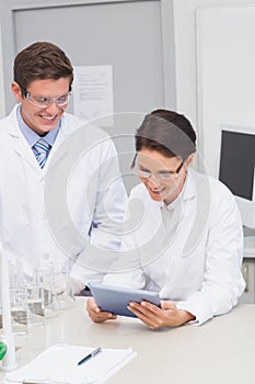 Smiling scientists using tablet