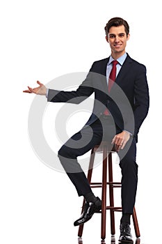 Smiling seated businessman is presenting