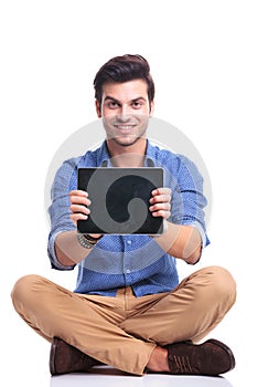 Smiling seated man showing the screen of his tablet