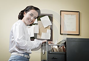 Smiling secretary searching files in the filing cabinet