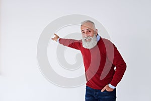 Smiling senior bearded man pointing backwards at copy space