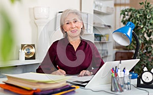Smiling senior business woman working on laptop in office
