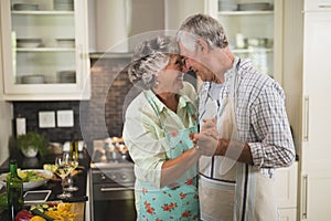 Smiling senior couple dancing in kitchen