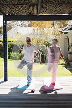 Smiling senior couple exercising at porch during sunny day