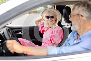 Smiling senior couple friends going summer vacation by car