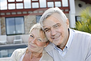 Smiling senior couple in front of home