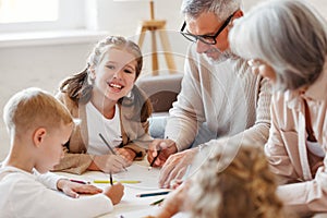 Smiling senior couple grandparents spending time with grandchildren at home on weekend