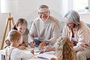 Smiling senior couple grandparents spending time with grandchildren at home on weekend