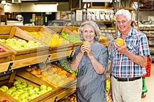 Smiling senior couple holding oranges