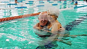 Smiling senior couple hugging in the swimming pool