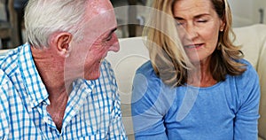 Smiling senior couple interacting with each other while having cup of coffee in living room