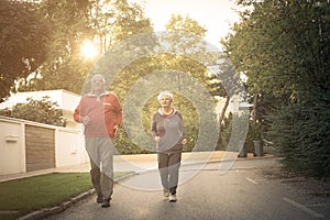 Smiling senior couple jogging in city park.