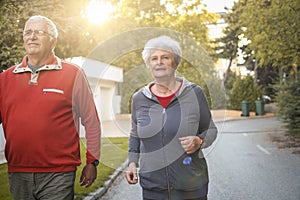 Smiling senior couple jogging in city park.