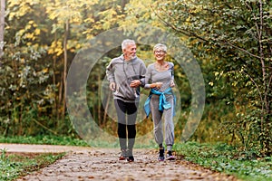 Smiling senior couple jogging in the park photo