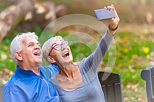 Smiling senior couple jogging in the park taking selfie