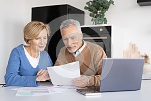 Smiling senior couple looking at sheet of paper together
