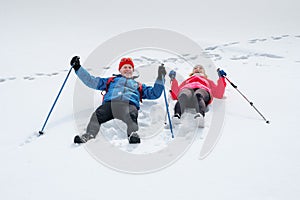 Smiling senior couple lying on snow outdoors and happy laugh.