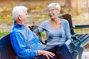 Smiling senior couple sitting in the park talking