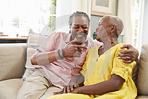 Smiling Senior Couple Sitting On Sofa At Home Together