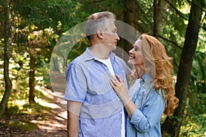 Smiling senior couple standing in park hugging each other together and smiling