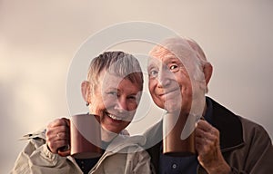 Smiling Senior Couple Toasting with Mugs