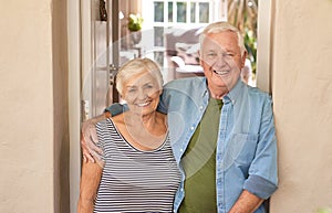 Smiling senior couple welcoming at their front door