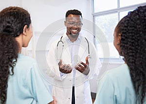 Smiling senior doctor talks to junior healthcare assistant, standing in hospital photo