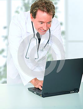 Smiling Senior Doctor Using Laptop In His Office