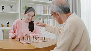 Smiling senior elderly having fun playing chess game with beautiful daughter at