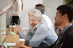 Smiling senior employee discussing email with african colleague photo