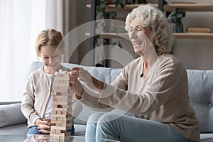 Happy senior grandmother and granddaughter play wooden stack game photo