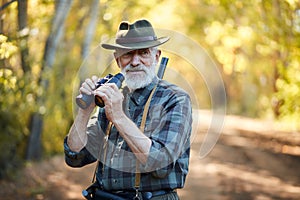 Smiling senior hunter use binoculars