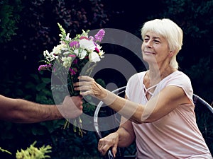 Elderly woman get a beautiful bouquet of field flowers.