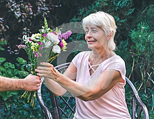 Elderly woman get a beautiful bouquet of field flowers.