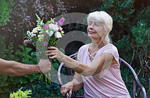 Elderly woman get a beautiful bouquet of field flowers.