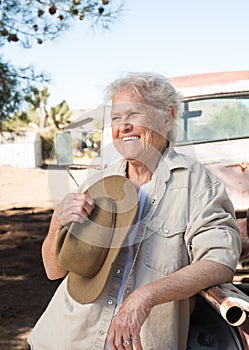 Smiling senior lady leaning against a vintage pickup truck