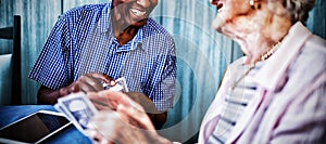 Smiling senior male and female friends playing cards