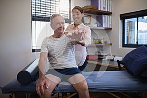 Smiling senior male patient and female doctor looking at hand