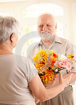 Smiling senior man bringing flowers