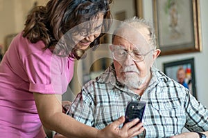 A Smiling senior man and caregiver with smartphone are doing a videocall photo