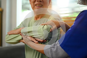 Smiling senior man exercising with his physiotherapist at home. Healthcare concept