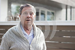 Smiling senior man in front of house